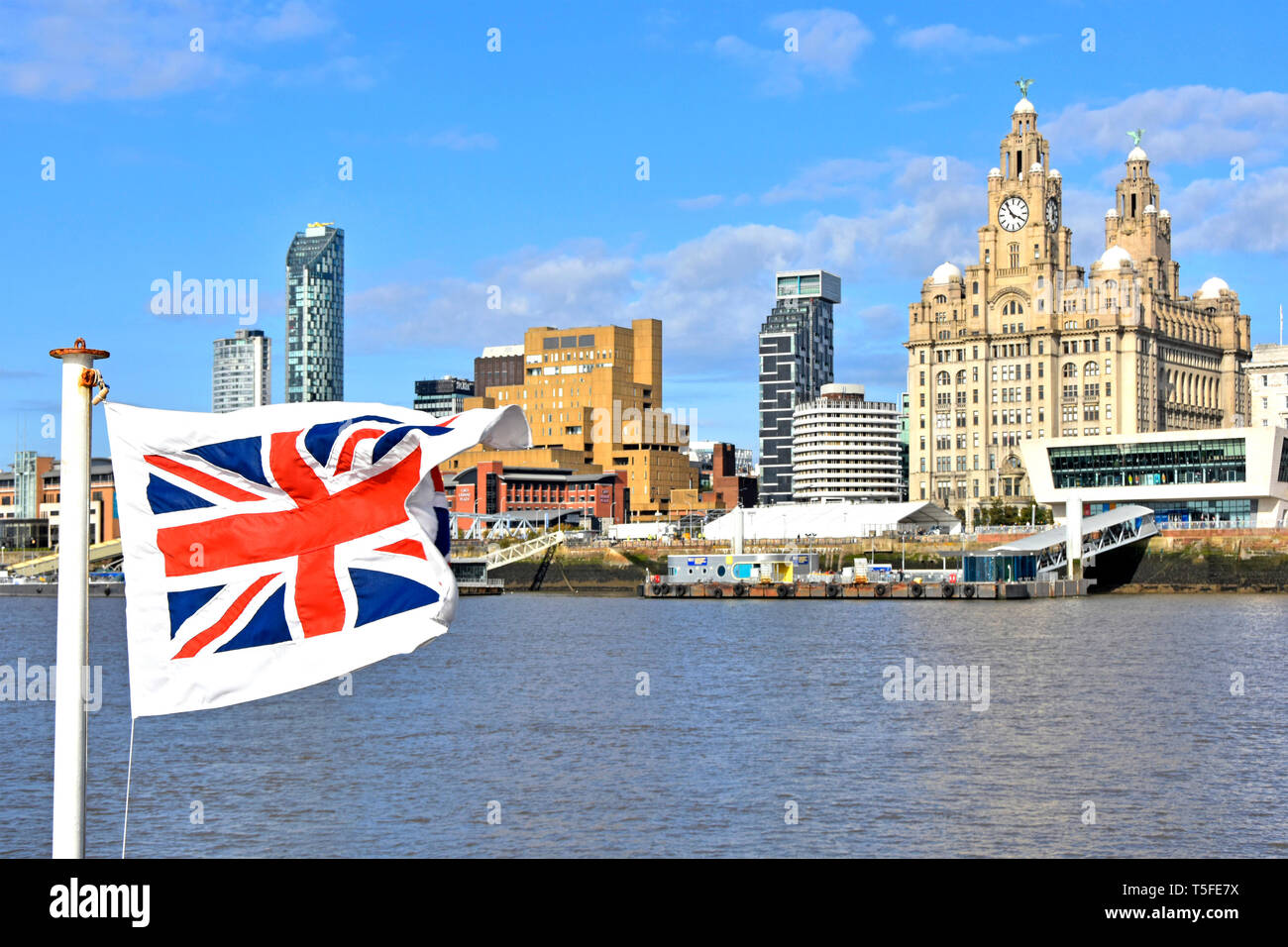 Union Jack flag on Mersey ferry boat Liverpool waterfront skyline famous iconic & historic Royal Liver Building with modern apartment buildings UK Stock Photo