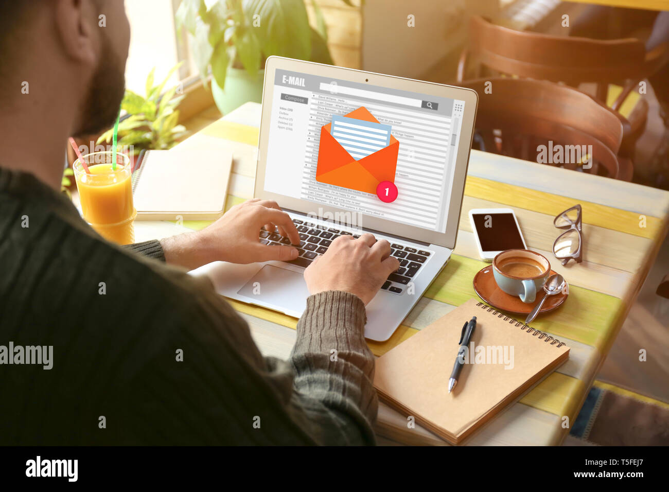 Young man with laptop checking an email in cafe Stock Photo