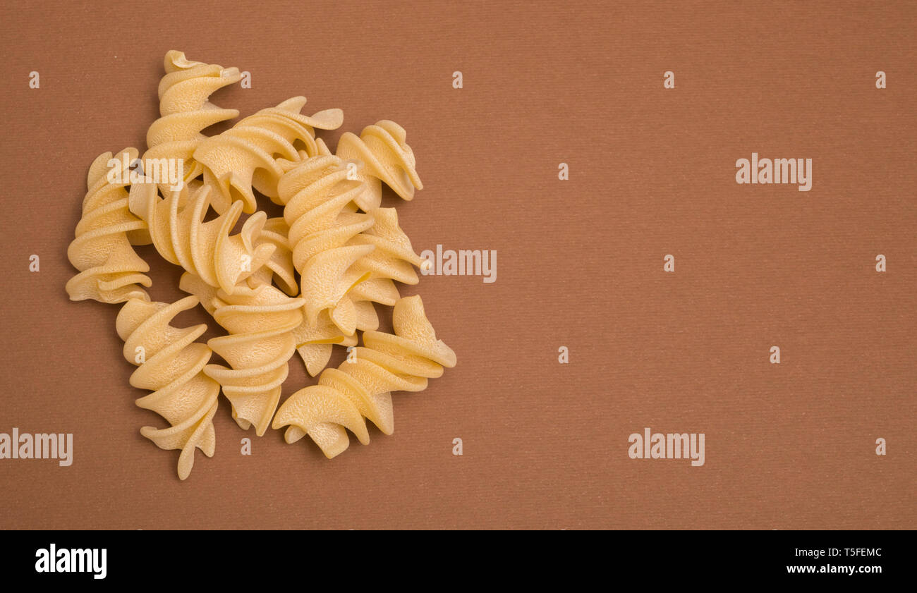 giant fusilli pasta helices on brown cardboard background Stock Photo