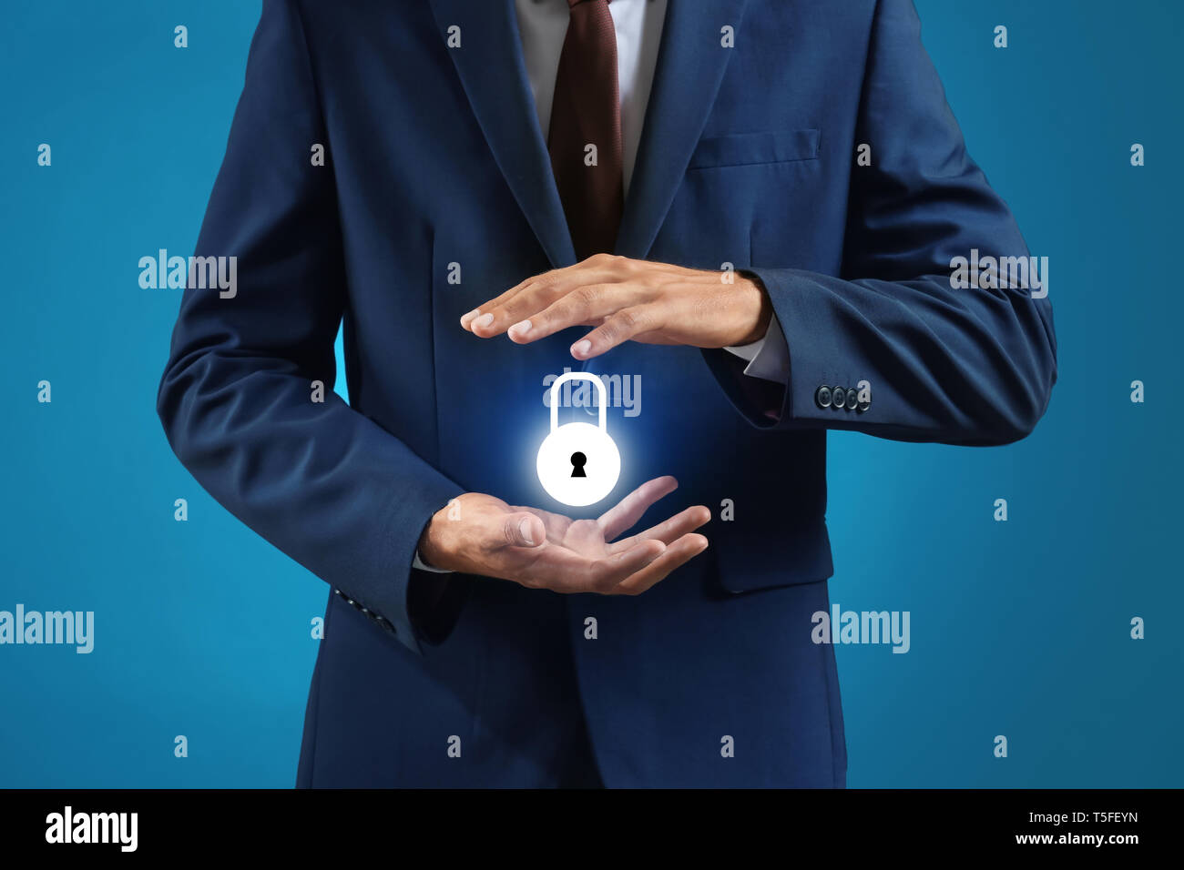 Businessman with glowing padlock icon on blue background. Data security concept Stock Photo