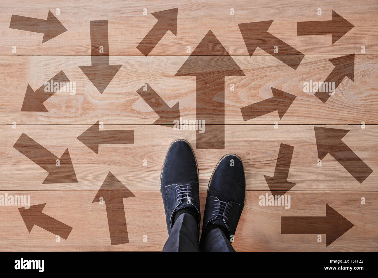 Man Standing On Wooden Floor With Arrows Pointing In