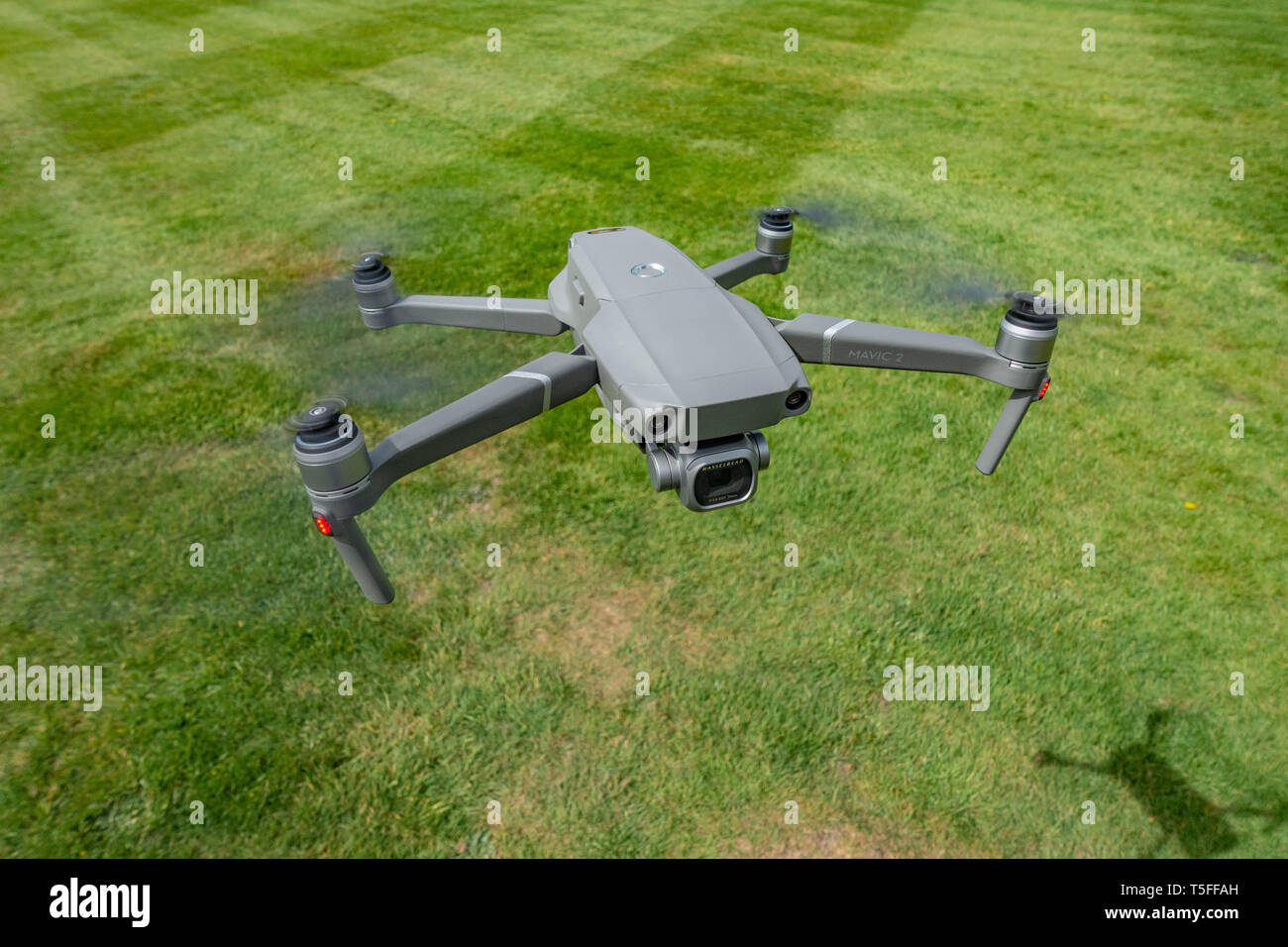 Looking down birds eye view onto a flying DJI Mavic 2 PRO personal Drone flying very low near to the ground Stock Photo