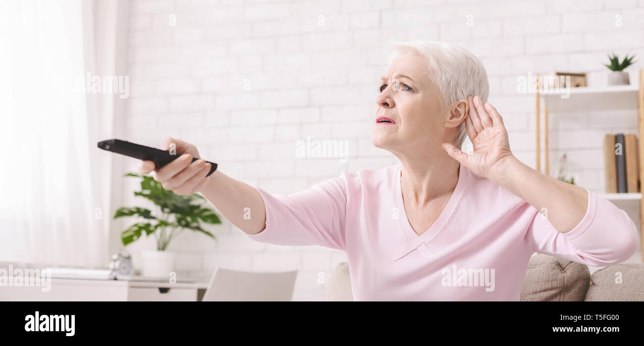 Elderly woman rising tv set volume with remote control Stock Photo Alamy