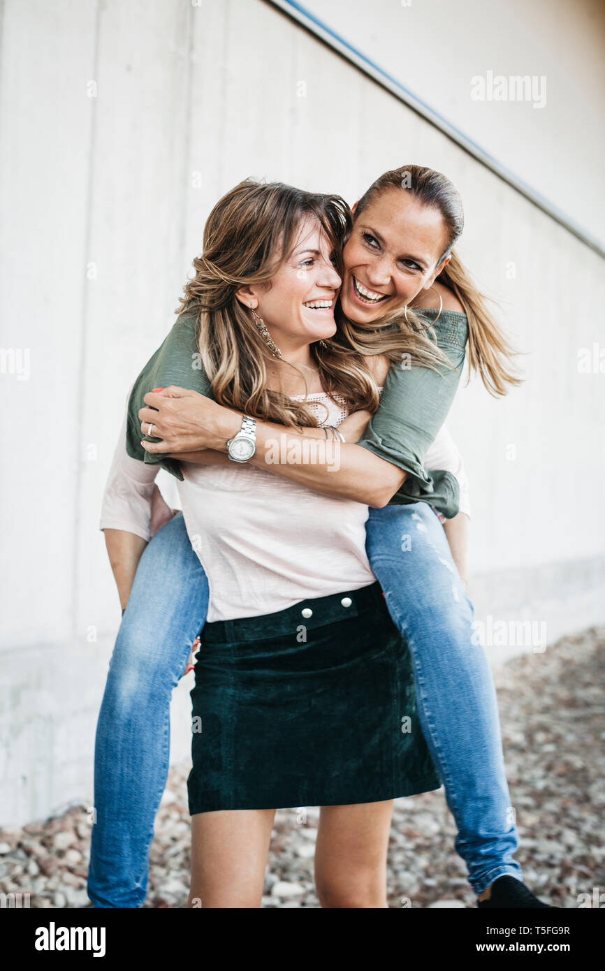 Girl giving her friend a piggyback ride stock photo