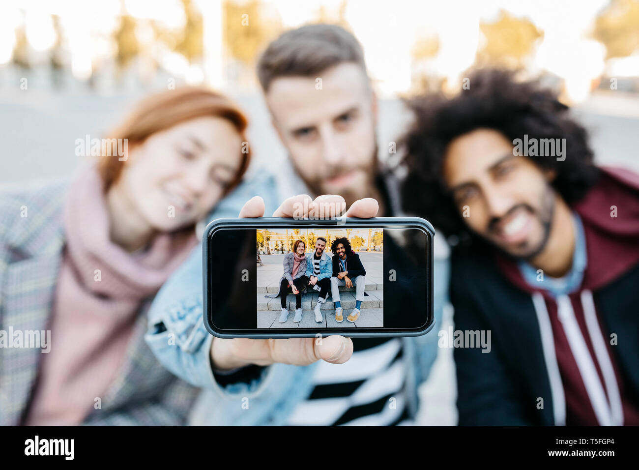 Three friends showing a selfie on camera phone Stock Photo