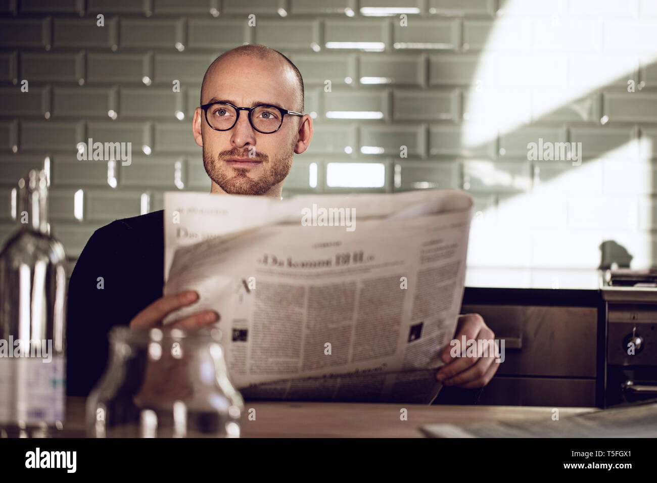 Man sitting in kitchen, reading newspaper Stock Photo