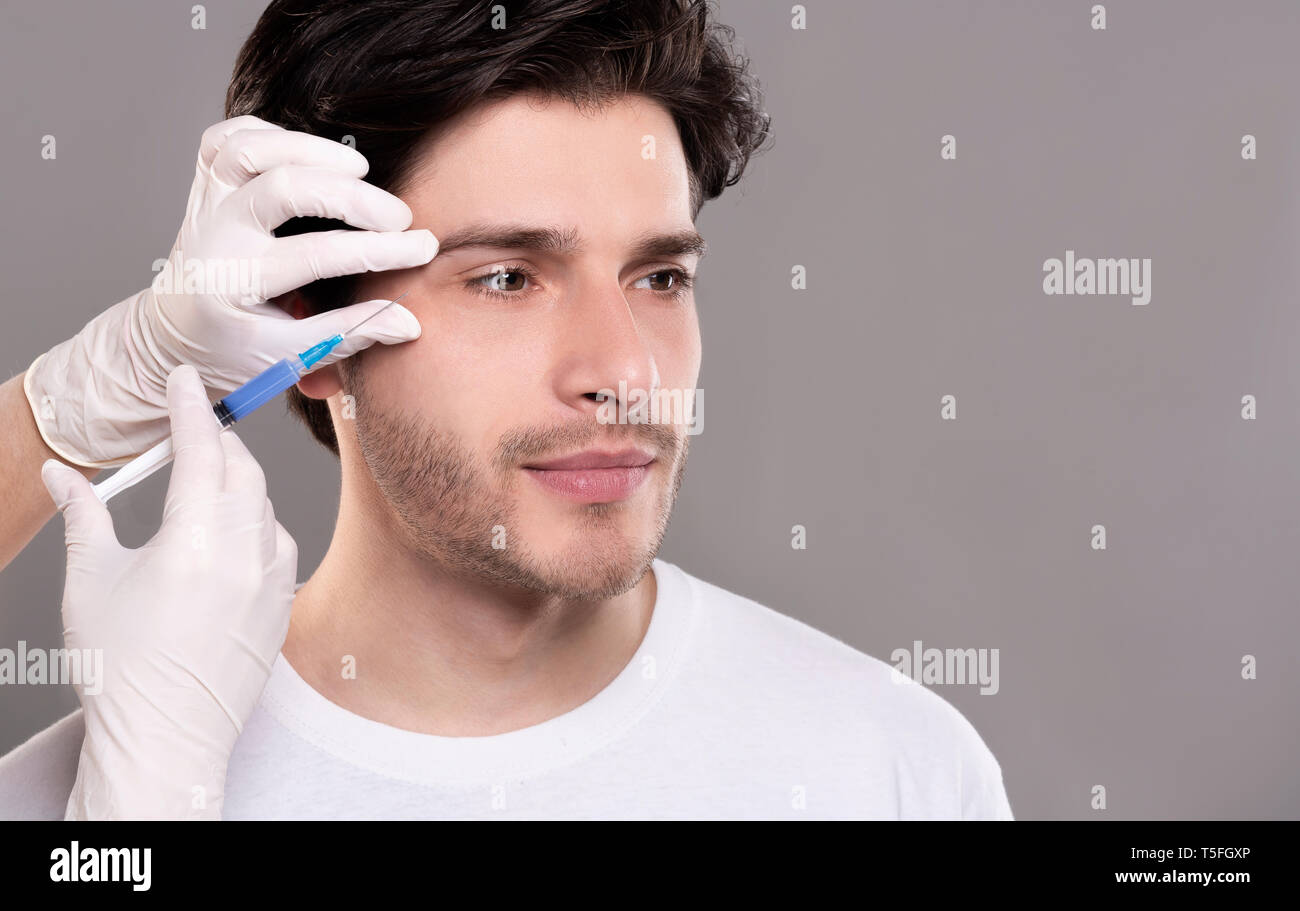 Millennial guy getting surgery filling of facial wrinkles Stock Photo
