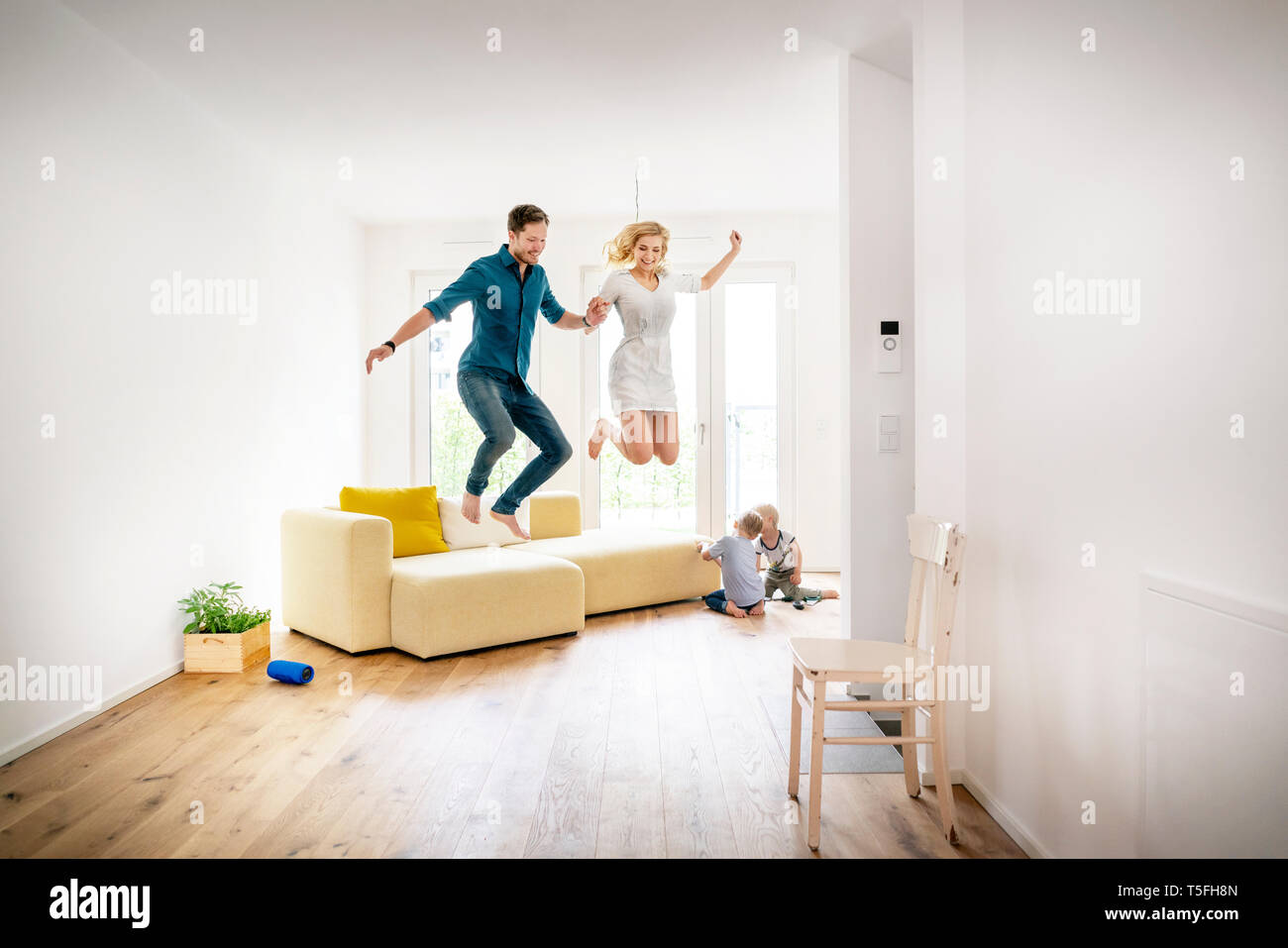 Happy family moving into their new home, parents jumping for joy Stock Photo