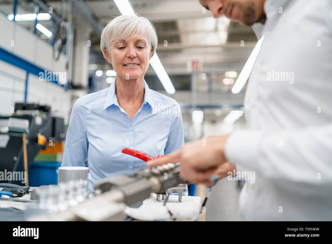 Businessman and senior businesswoman examining workpiece in a factory Stock Photo