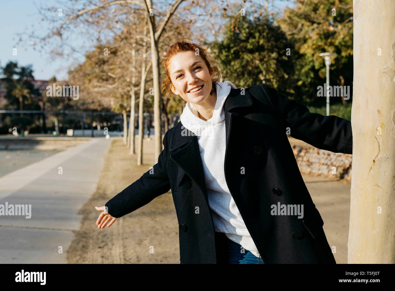 Portrait of happy redheaded young woman in a city park Stock Photo - Alamy