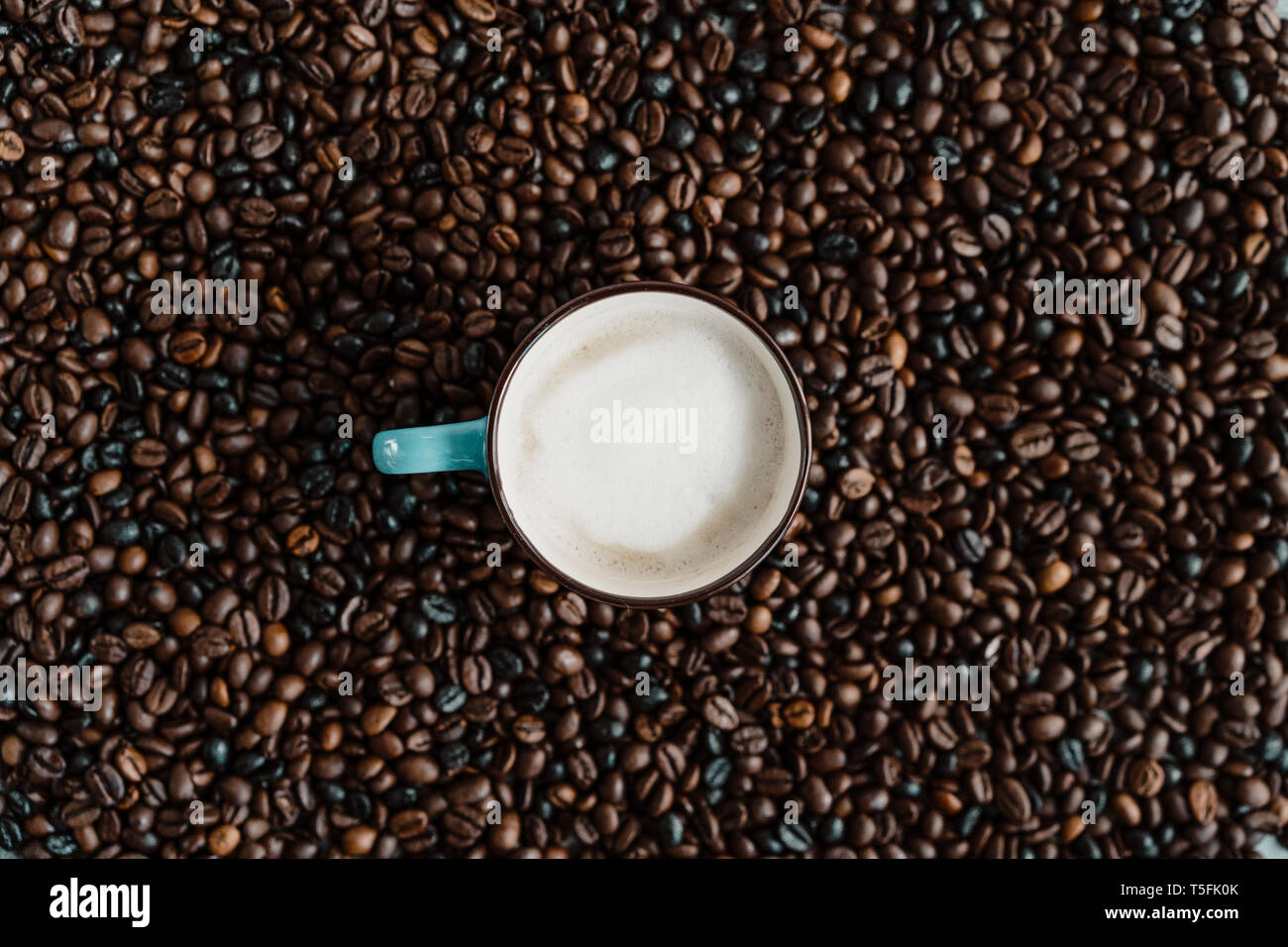 Cup of white coffee between coffee beans Stock Photo