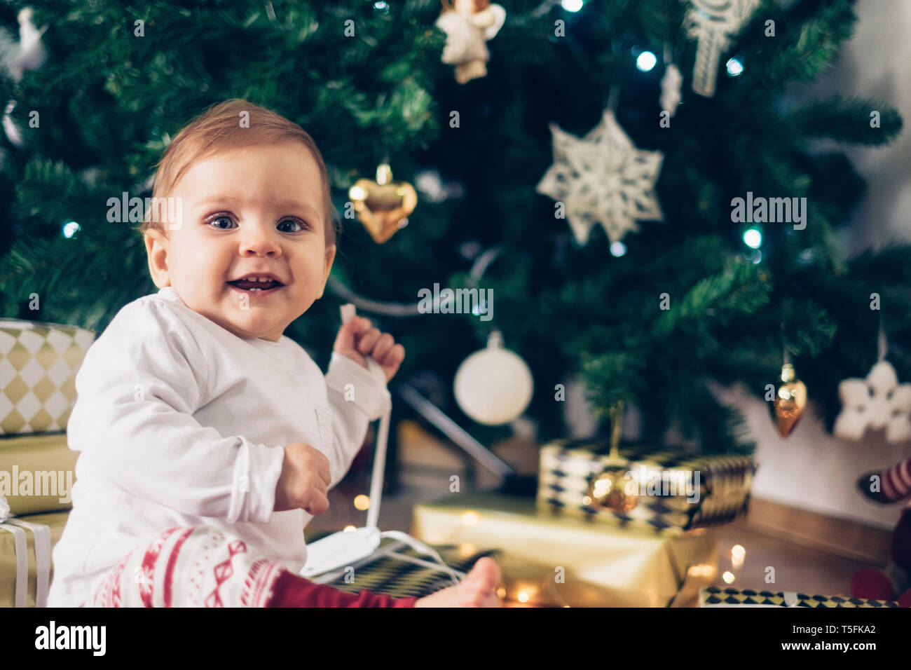 Portrait of smiling baby girl unpacking Christmas gifts Stock Photo
