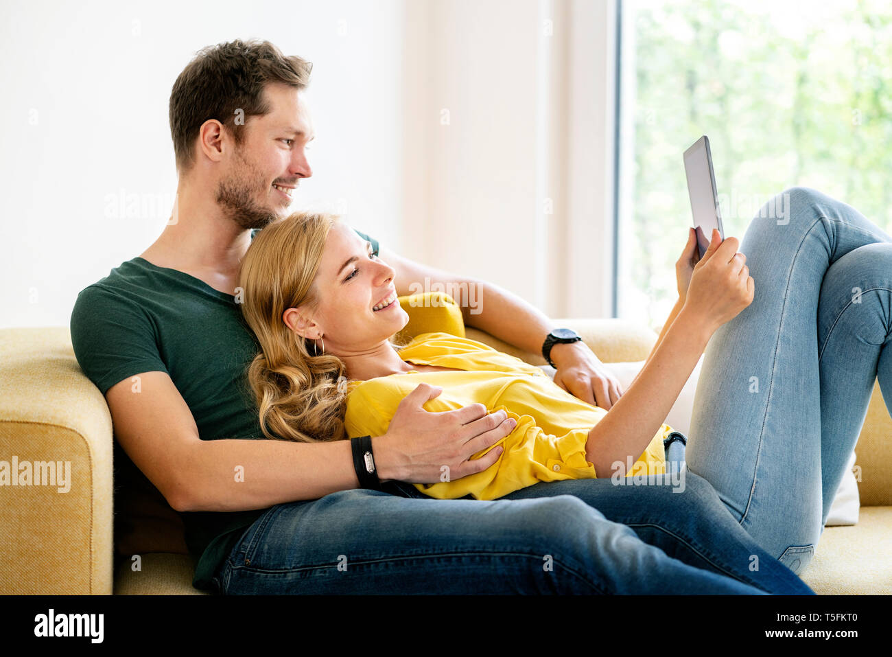 Couple sitting on couch in their new home, using digital tablet Stock Photo