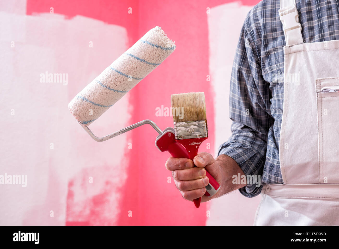 Caucasian house painter worker in white overalls, holding brush and