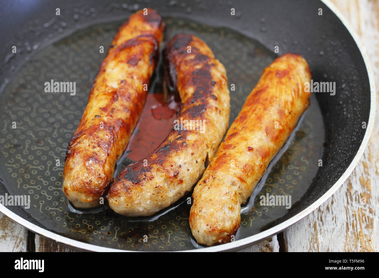 Three fried British pork sausages in frying pan Stock Photo Alamy