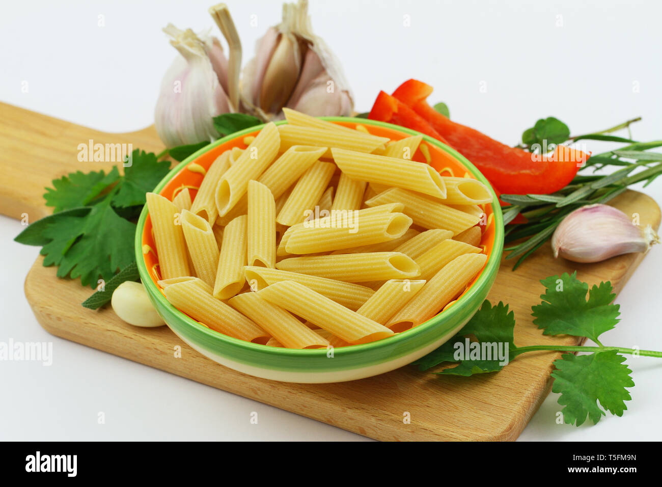 Cooking ingredients: raw pasta, garlic, red pepper and fresh herbs Stock Photo
