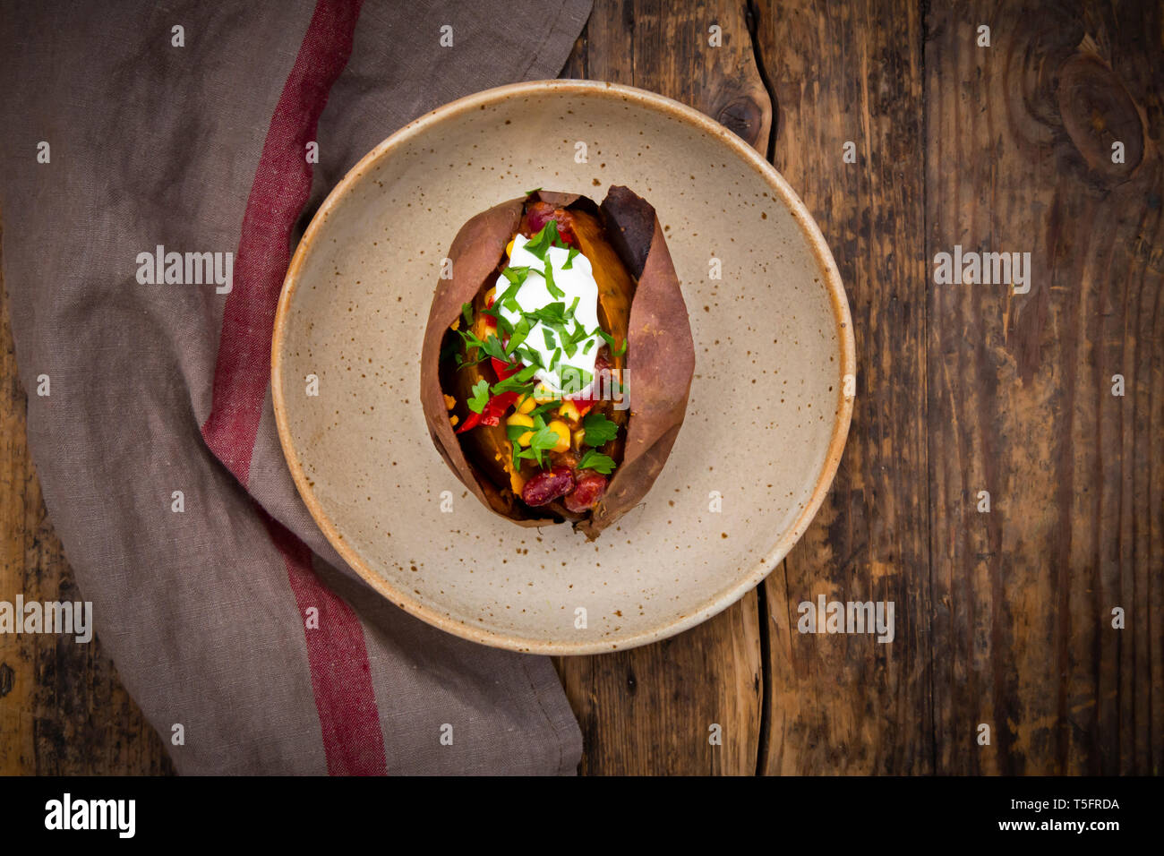 Sweet potato kumpir with chili con carne, sour cream and coriander Stock Photo