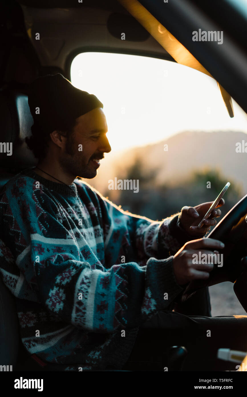 Young man on a road trip, using smartphone Stock Photo