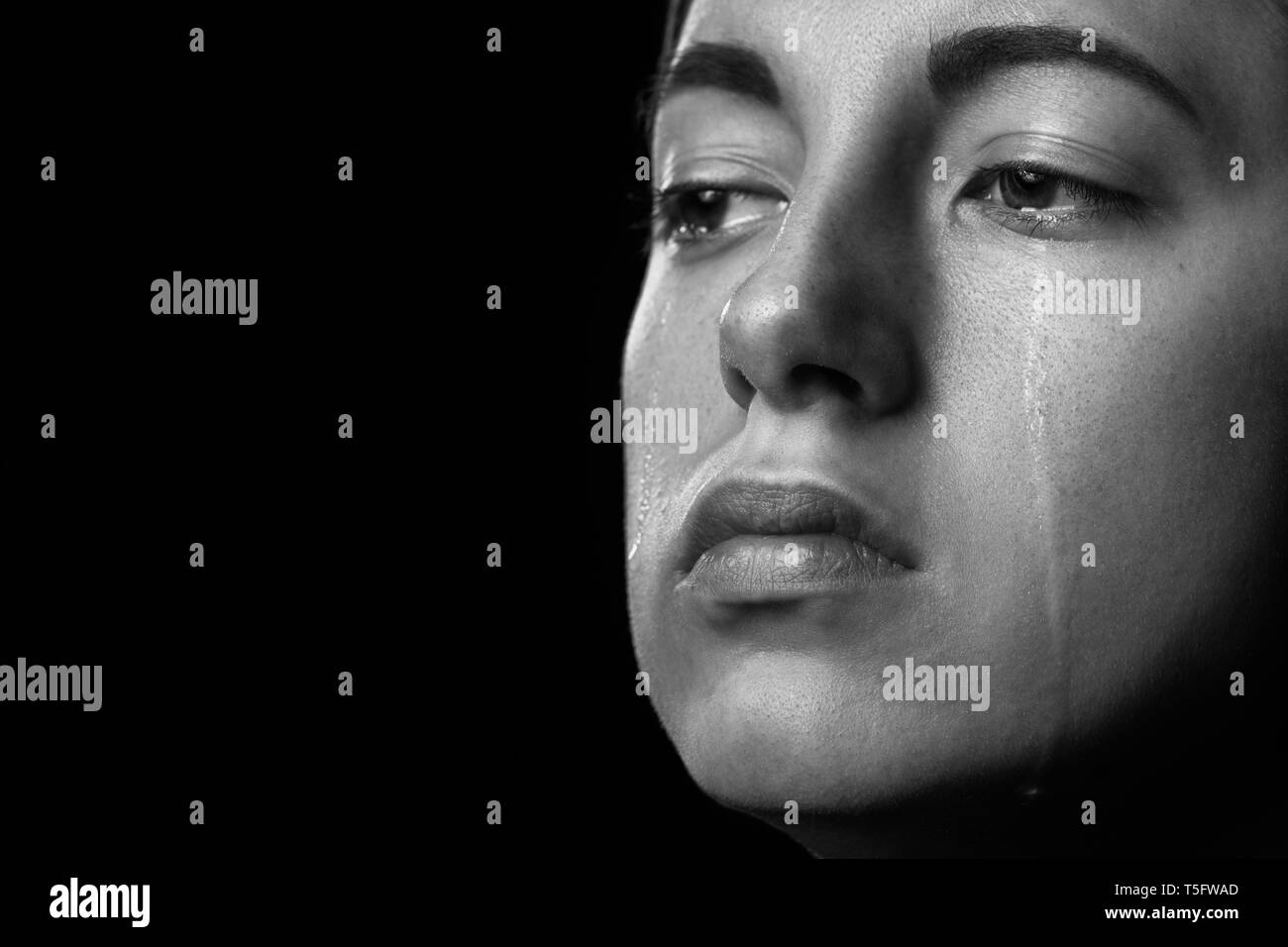 sad woman crying on black background, closeup portrait, monochrome Stock Photo