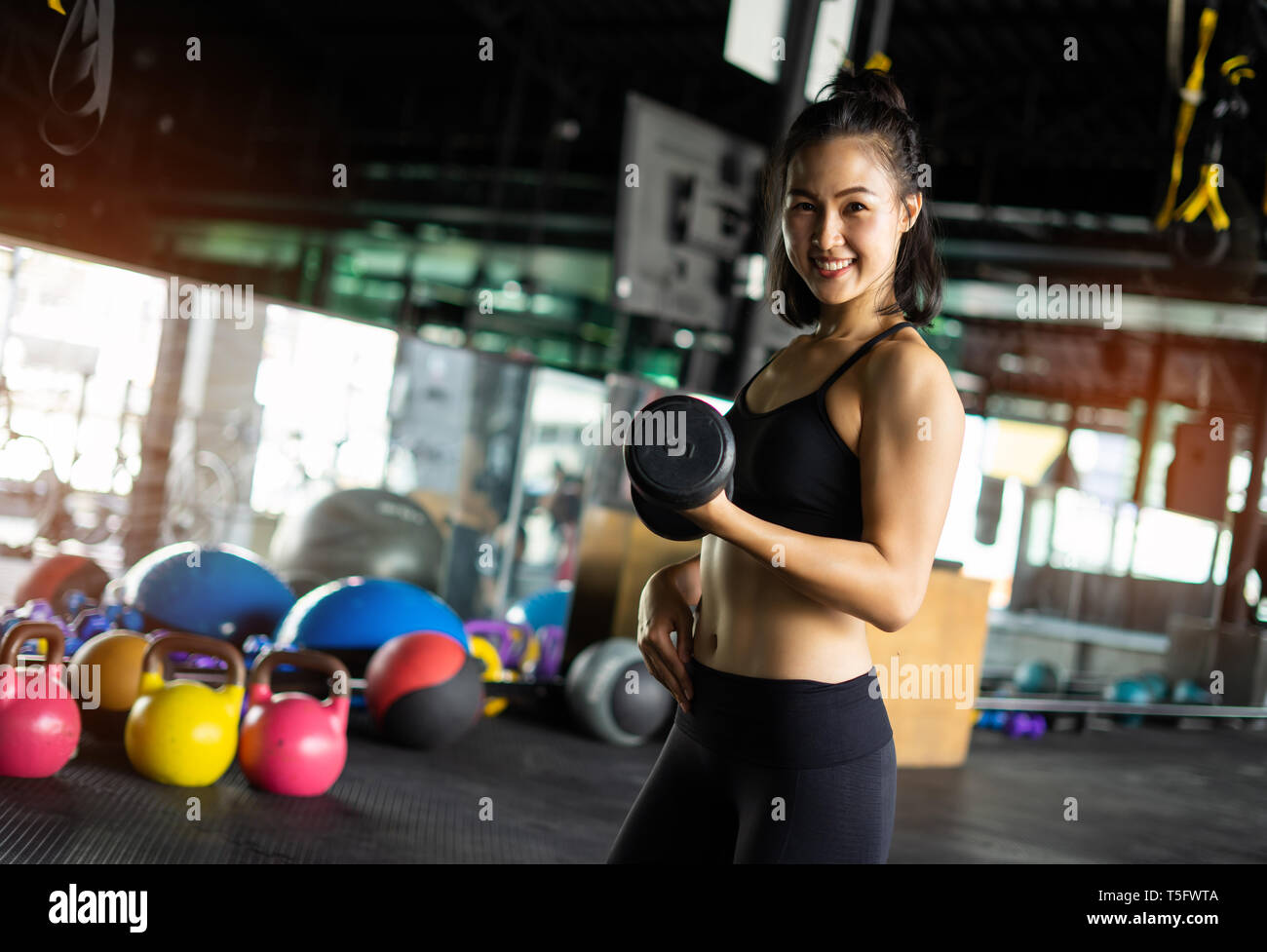 Sporty beautiful woman exercising with dumbbell weight training equipment with blurry background, Healthy life and gym exercise equipments and sports  Stock Photo