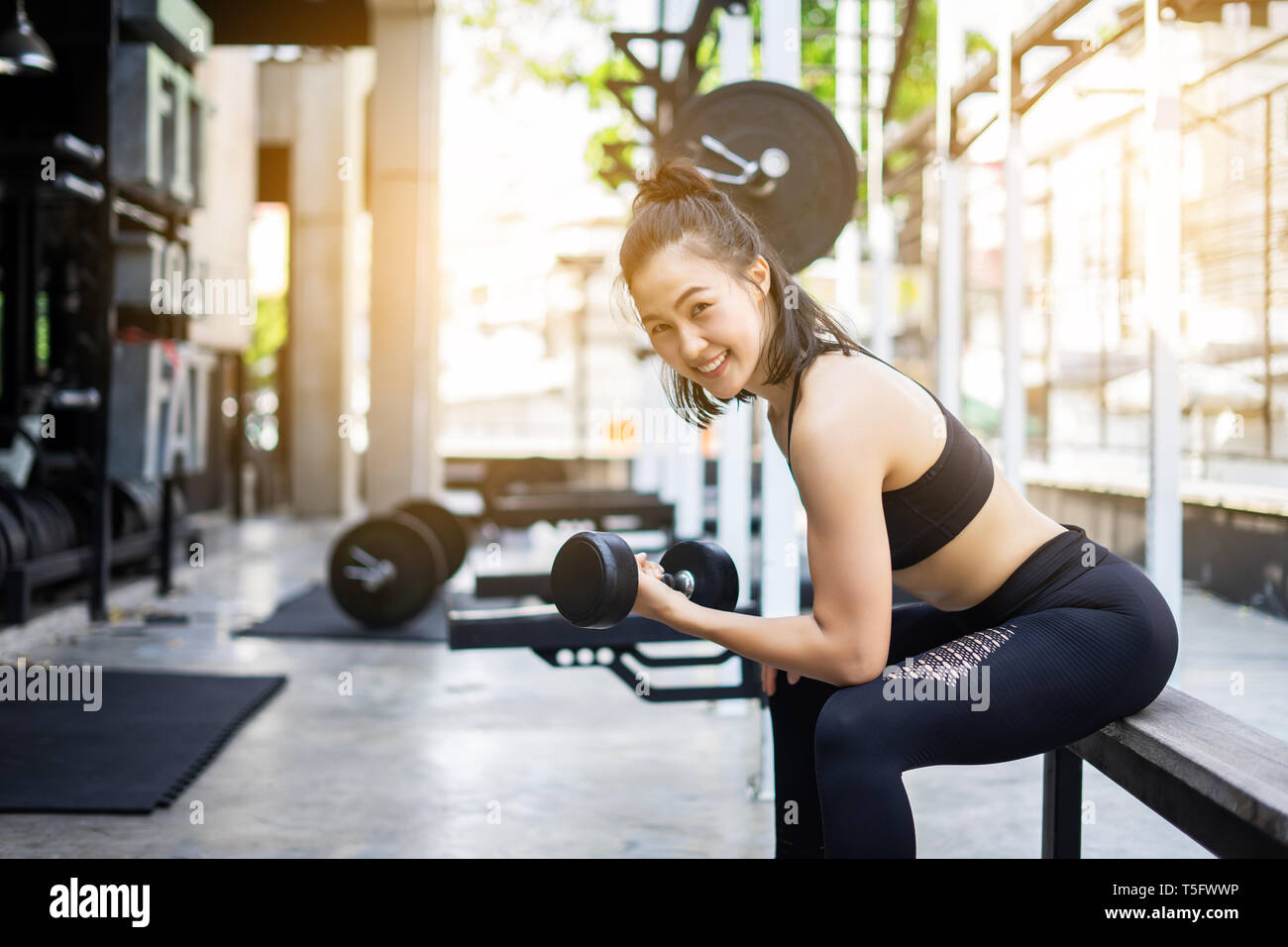 Sporty beautiful woman exercising with dumbbell weight training equipment with blurry background, Healthy life and gym exercise equipments and sports  Stock Photo