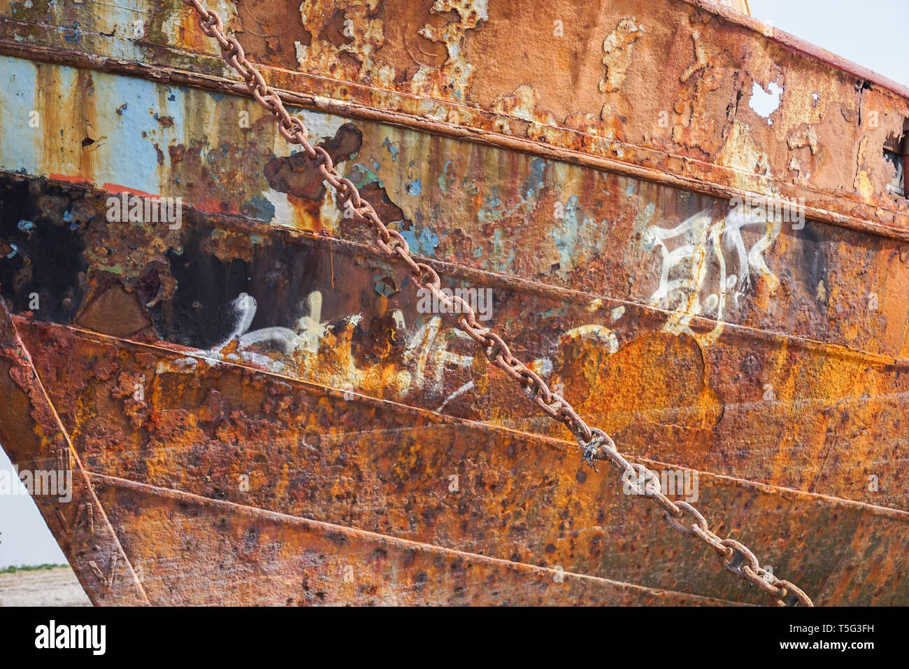 A ship wrecked fishing boat aground and abandoned rusting away on the shore line at Rampside in Cumbria Stock Photo