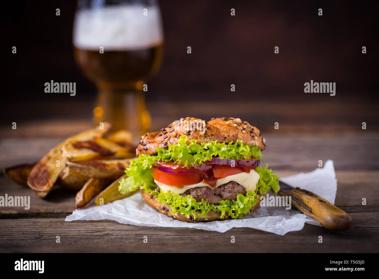 Home made hamburger with green salad on brown wooden background. Stock Photo