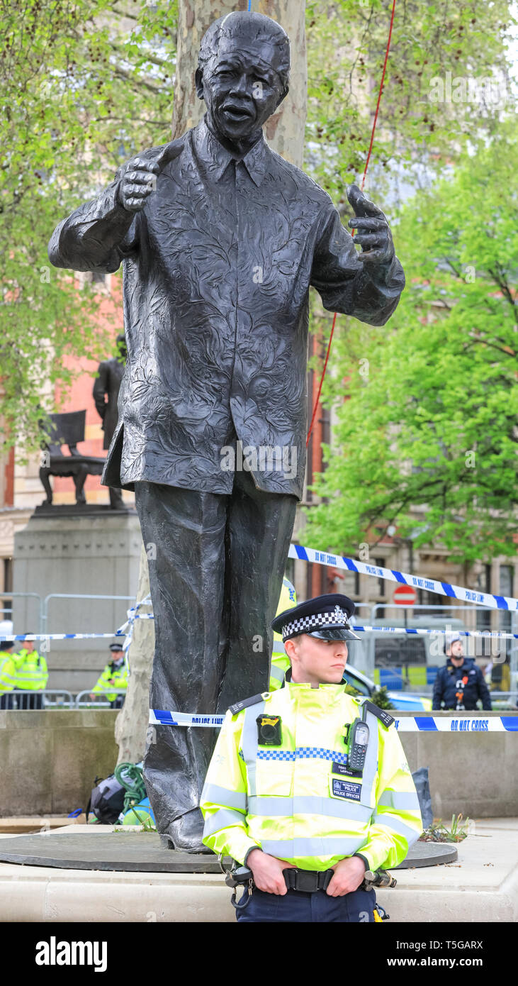 Westminster, London, UK, 24th April 2019. Police attempt to remove Extinction Rebellion and climate change protesters who have been camping high up in a tree on Parliament Square for several days. Nelson Mandela statue in the foreground. Credit: Imageplotter/Alamy Live News Stock Photo