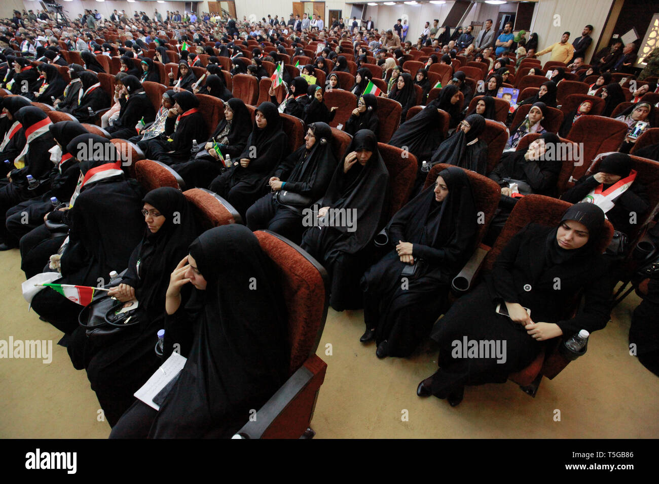 Baghdad, Iraq. 24th Apr, 2019. Women holding flags of Iran and Iraq attend a conference organized by the predominantly Shia Muslim Popular Mobilization Forces (PMF) to honour Iranian fighters who died fighting the so-called Islamic State (IS) terror group. Credit: Ameer Al Mohammedaw/dpa/Alamy Live News Stock Photo