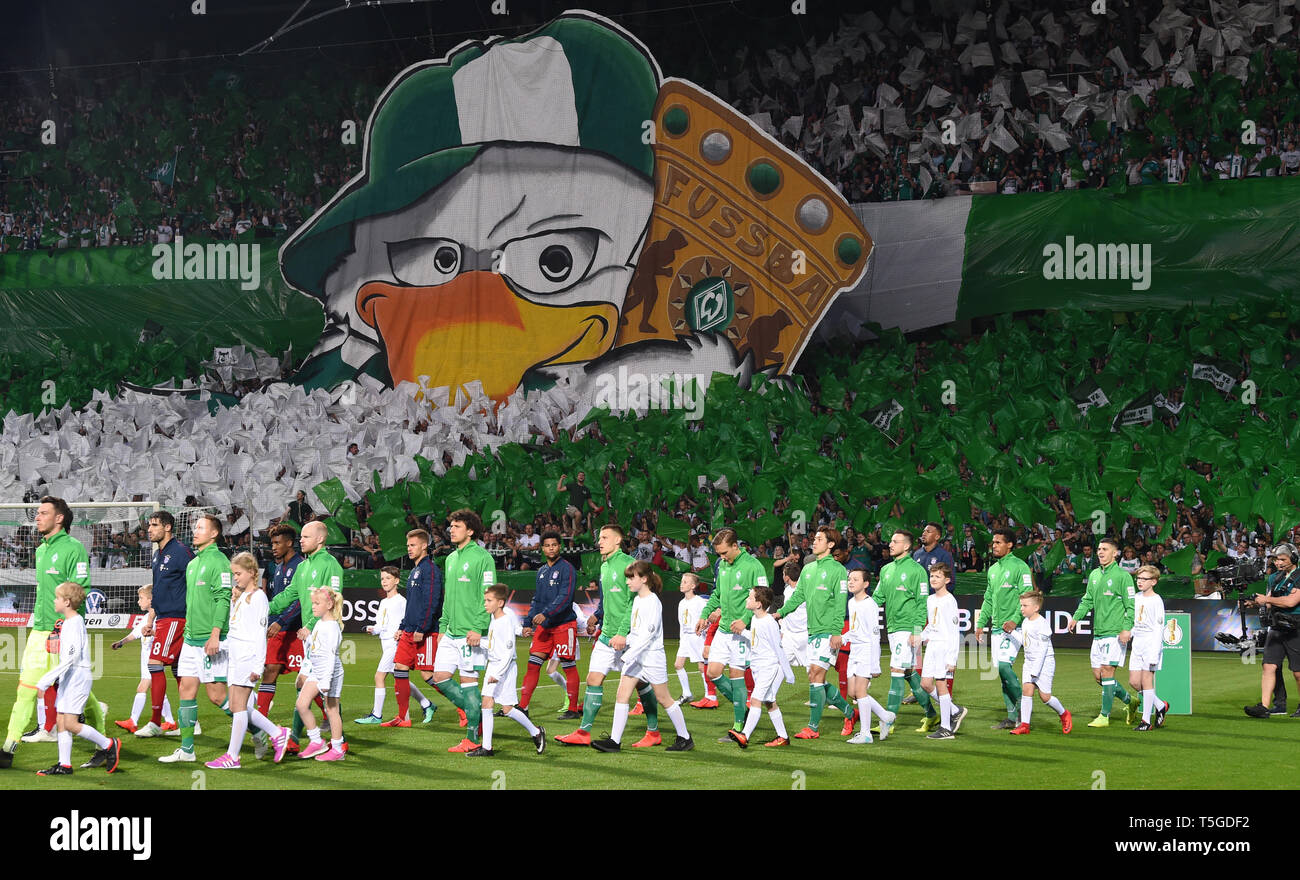 Bremen, Germany. 24th Apr, 2019. Soccer: DFB Cup, semi-final: Werder Bremen - FC Bayern Munich in the Weserstadion. Bremen's players run on the grass while their fans show a choreo before the kick-off (Important note: The DFB prohibits the use of sequence images on the Internet and in online media during the game (including half time). Blocking period! The DFB permits the publication and further use of images on mobile devices (especially MMS) and via DVB-H and DMB only after the end of the game.) Credit: Carmen Jaspersen/dpa/Alamy Live News Stock Photo