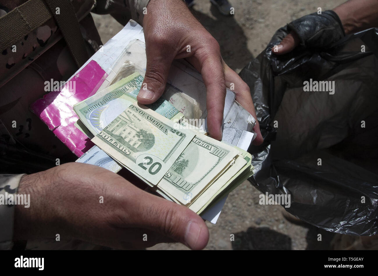 May 2, 2006 - Bayji, Salah ad Din, Iraq - An Iraqi army officer holds up moeny found on a man suspected of selling black market fuel at a truck stop just outside Bayji, Iraq May 2, 2006.Soldiers from the Iraqi army's 4th Battalion, 2nd Brigade, 4th Division, and the American's Abu Company, 1st Battalion, 187th Infantry Regiment have been cracking down on blackmarket fuel smugglers and sellers around the area of Bayji, Iraq. The insurgency and criminal gangs gain a lot of their funding from the smuggling of gas and oil to Turkey, Syria and Jordan, said officials with the 101st Airborne Divi Stock Photo