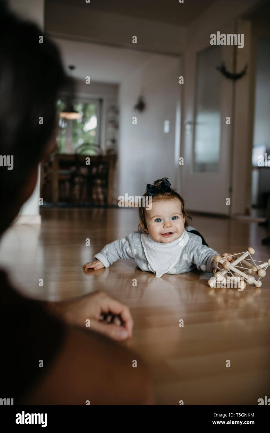 Baby girl lying on the floor playing with motor skill toy Stock Photo