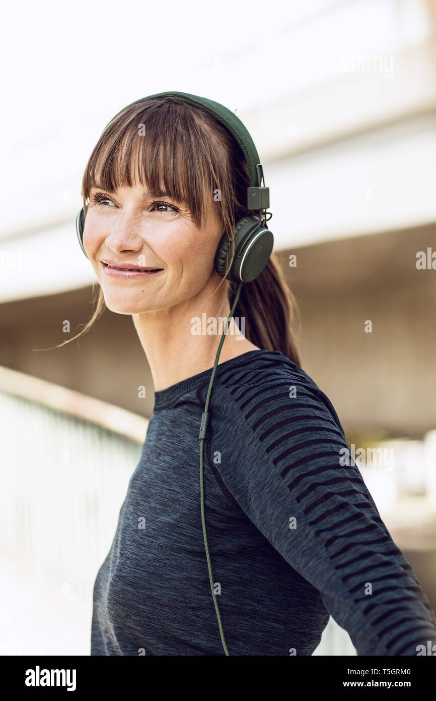 Sportive woman with headphones, doing her fitness training outdoors Stock Photo