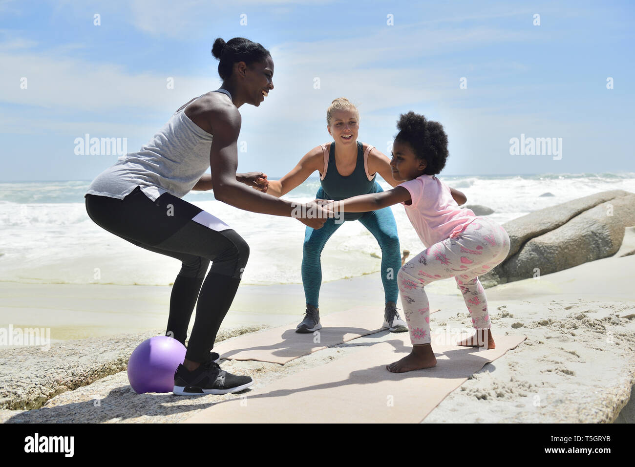 Mother with daughter and friend doing a fitness exercise on the beach Stock  Photo - Alamy