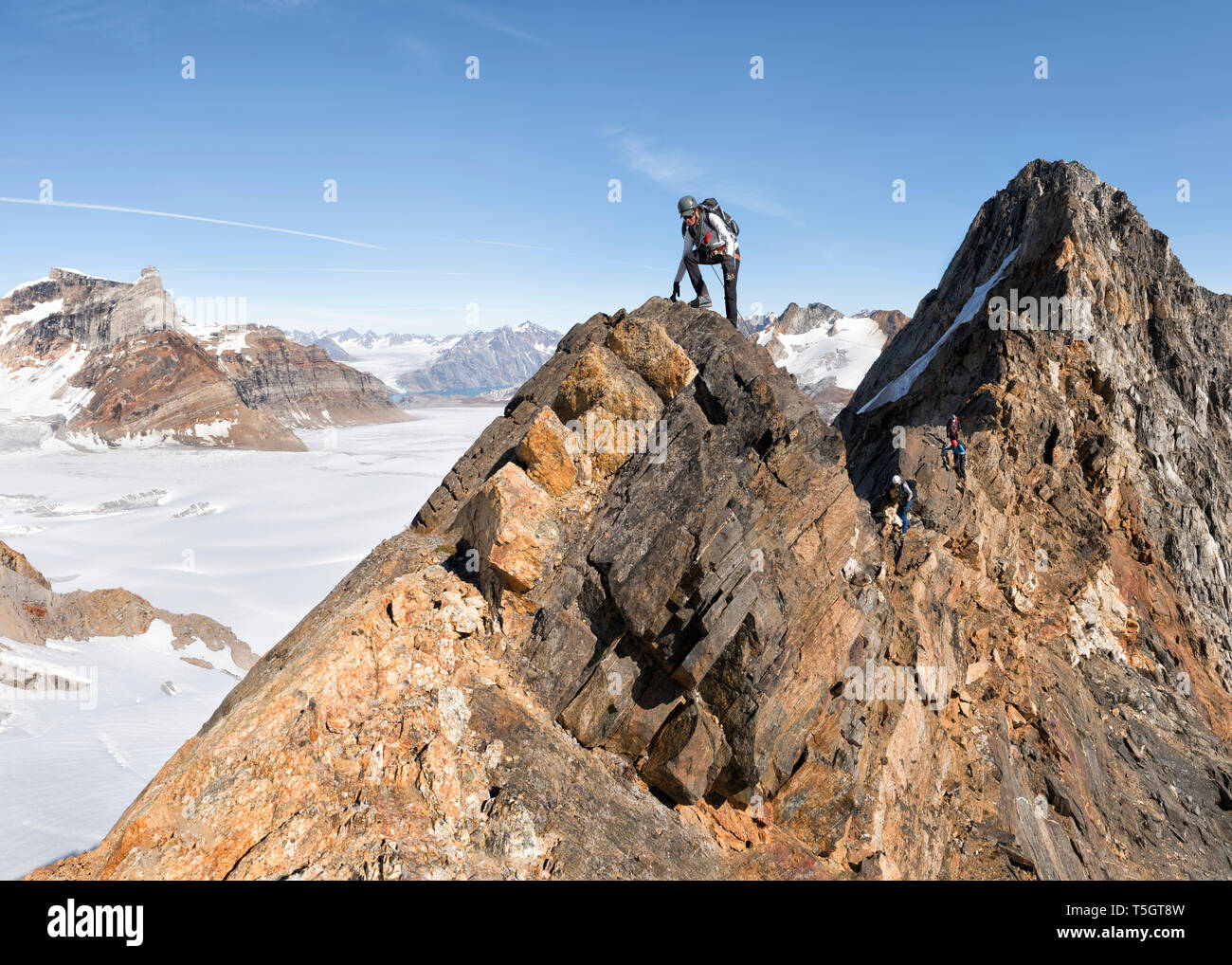 Greenland, Sermersooq, Kulusuk, Schweizerland Alps, mountaineer reaching summit Stock Photo
