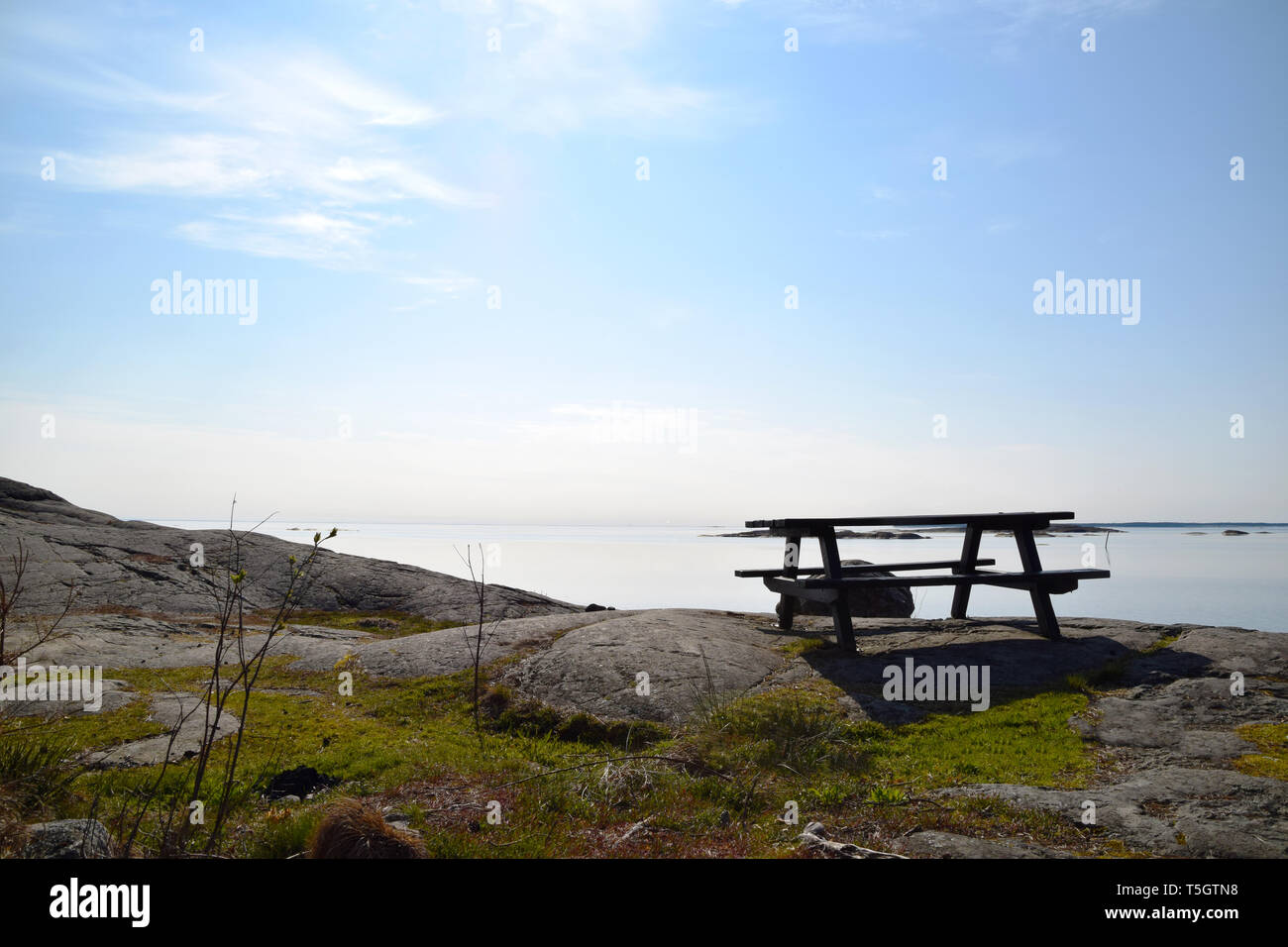 Empty picnic table and bench on the cliffs in the Swedish archipelago on a beautiful morning Stock Photo