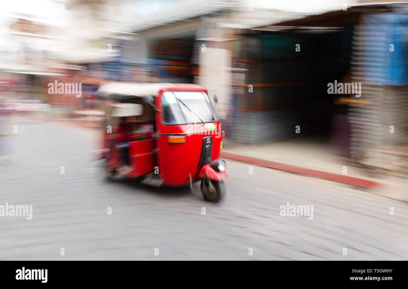 A speeding tuk tuk taxi or auto rickshaw with motion blur; Guatemala, Central America Stock Photo