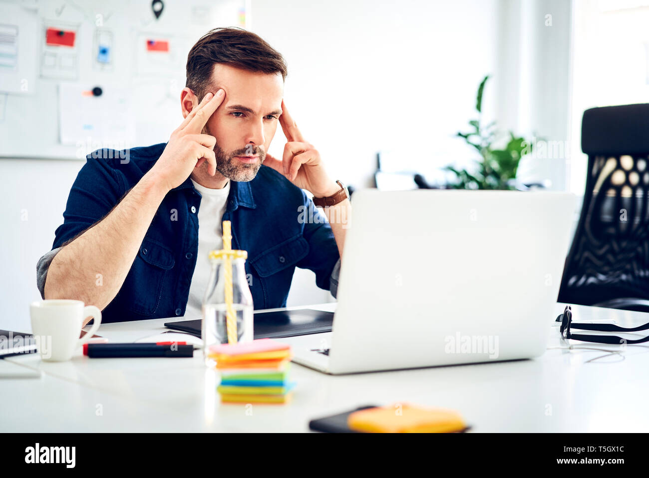 Focused businessman working on laptop at desk in office Stock Photo