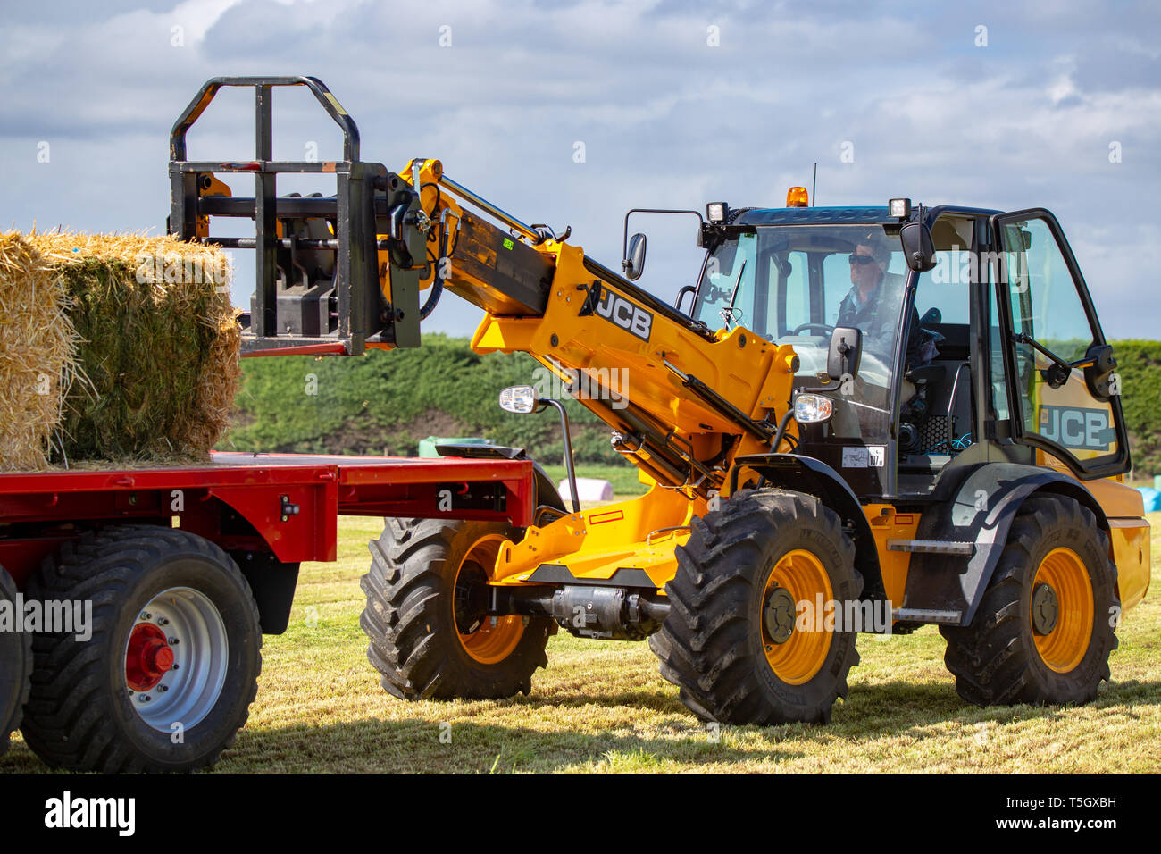 Kirwee, Canterbury, New Zealand, March 27 2019: A farmer demonstrates how the JCB telehandler works so well stacking haybales at the South Island Agri Stock Photo