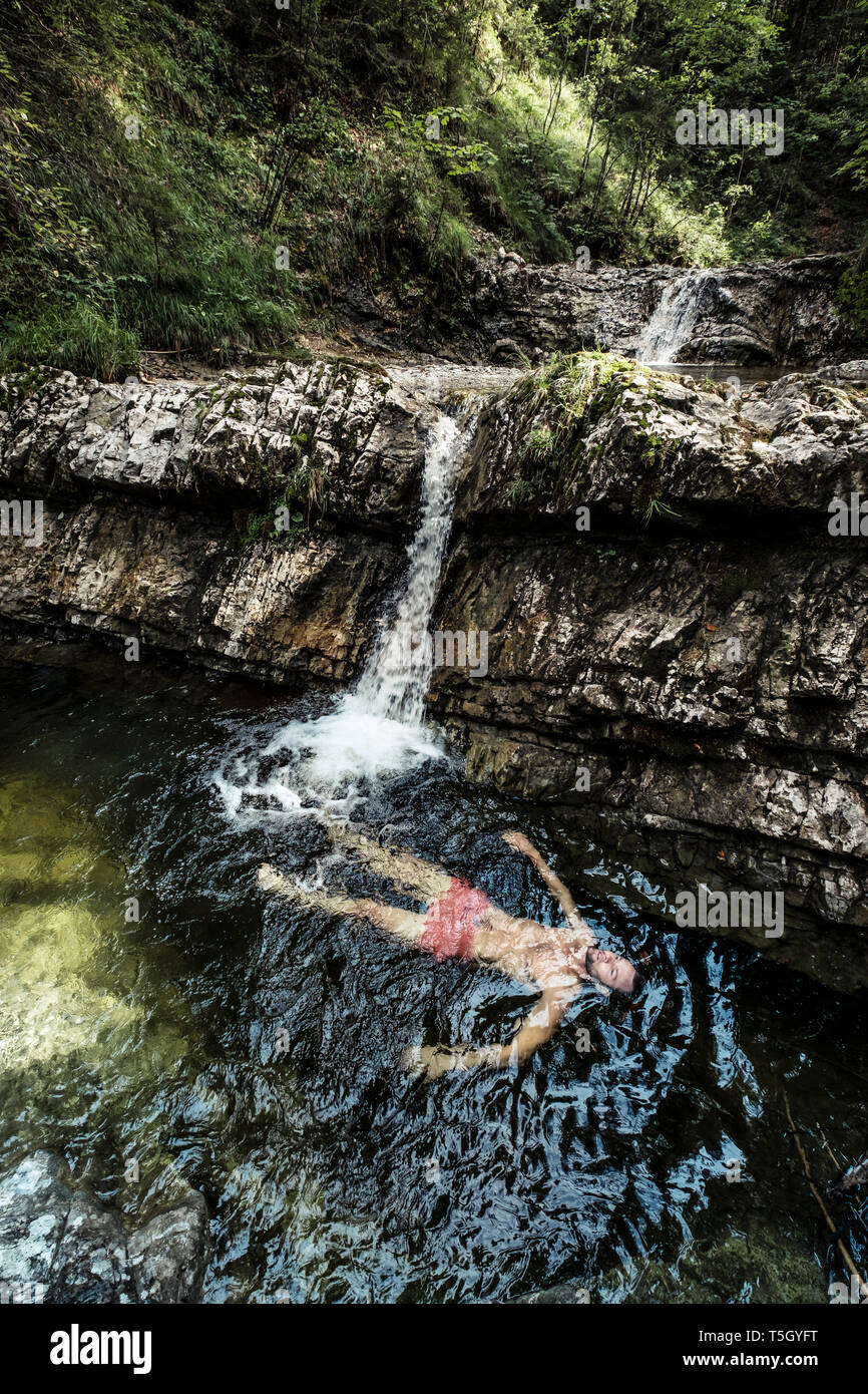 Germany, Upper Bavaria, Bavarian Prealps, lake Walchen, young man is swimming in a plunge pool Stock Photo