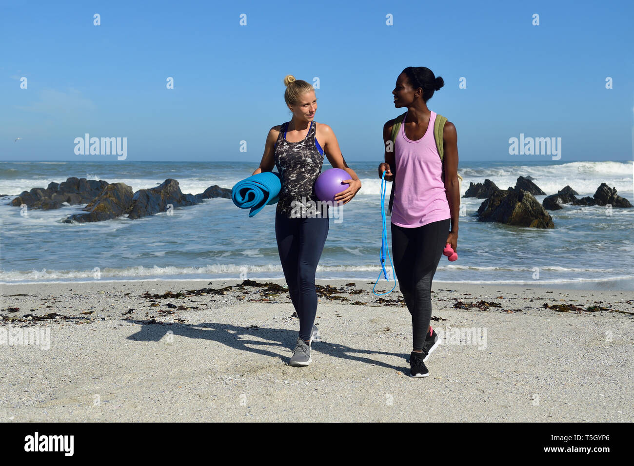 Two women with fitness equipment walking on the beach Stock Photo