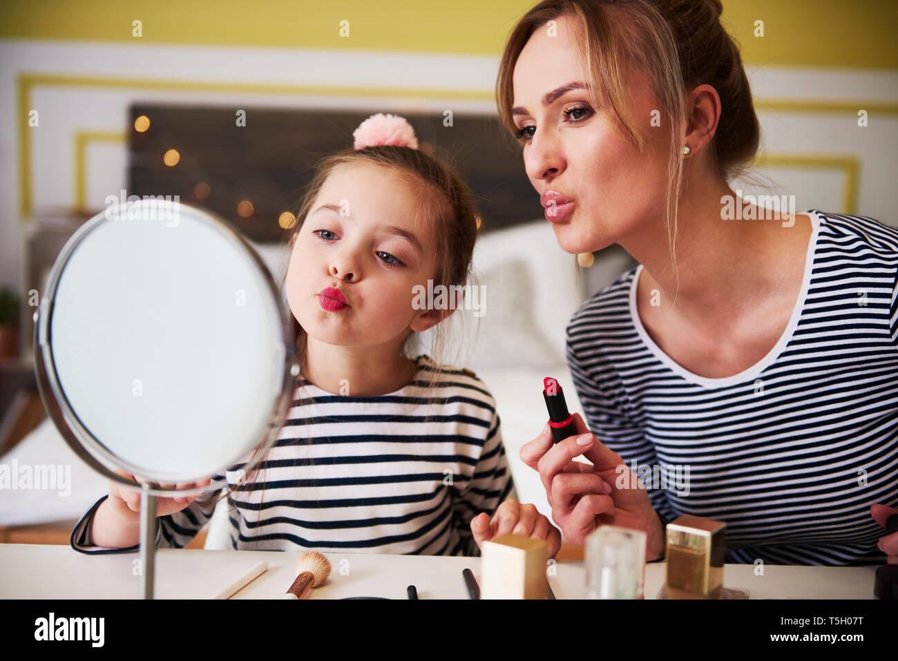 Mother and daughter applying make up together, using lipstick Stock Photo