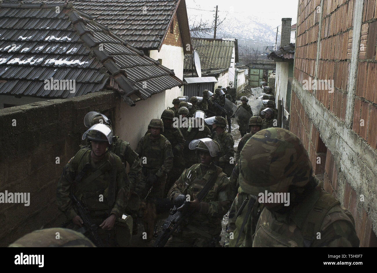 February 21, 2000 - Mitrovica, Kosovo, Yugoslavia - U.S. soldiers wait to head down a street in the Little Bosnia neighborhood of northern Mitrovica, Kosovo, Yugoslavia, to search for weapons caches in a joint operation with the French military Feb. 21, 2000. (Credit Image: © Bill Putnam/ZUMA Wire) Stock Photo