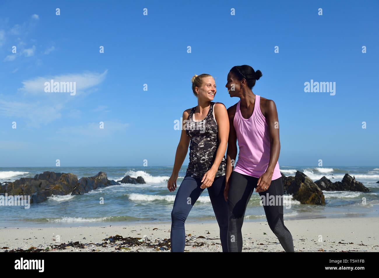 Two happy women walking on the beach Stock Photo