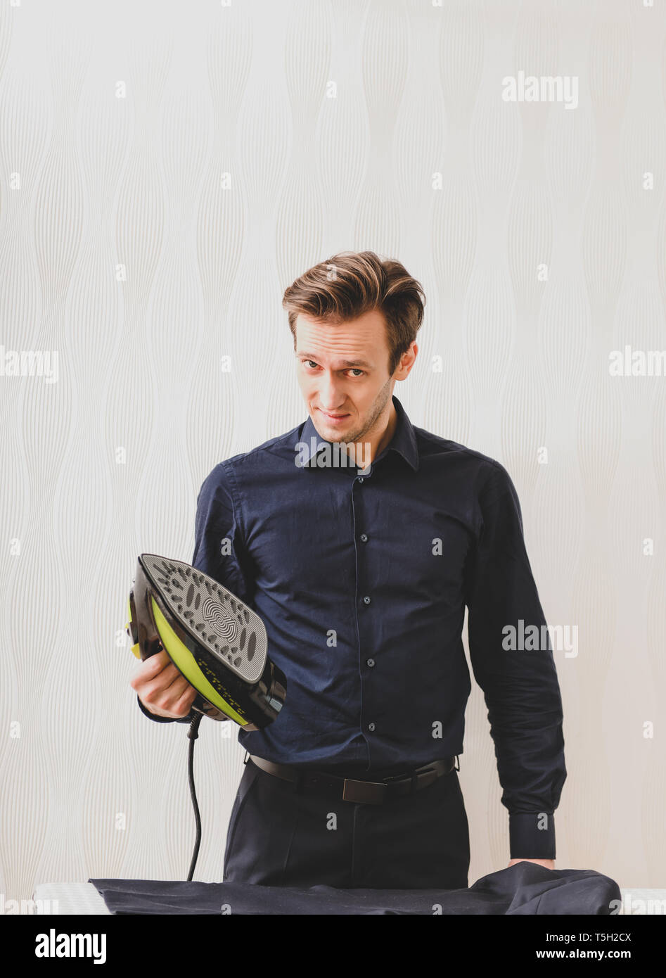 Single man is ironing shirt on board, at home. Housework concept. Stock Photo
