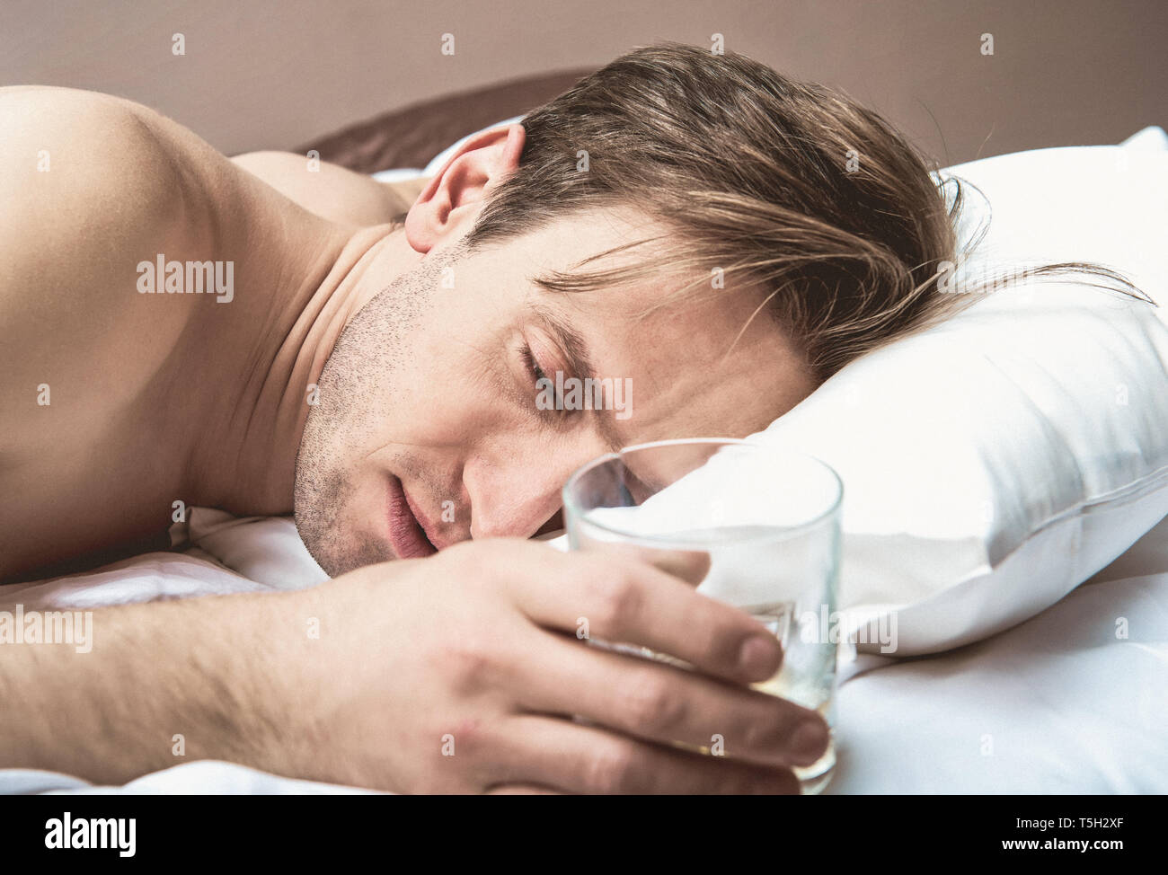 Woman sleeping with glass of alcohol in hand. Alcohol addiction. Stock Photo