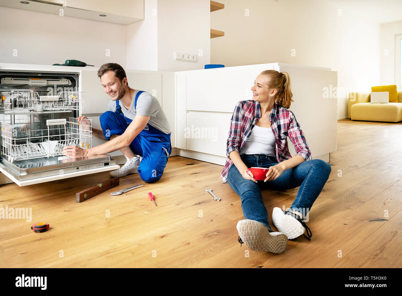 Couple fitting dishwasher in their new builtin kitchen Stock Photo Alamy