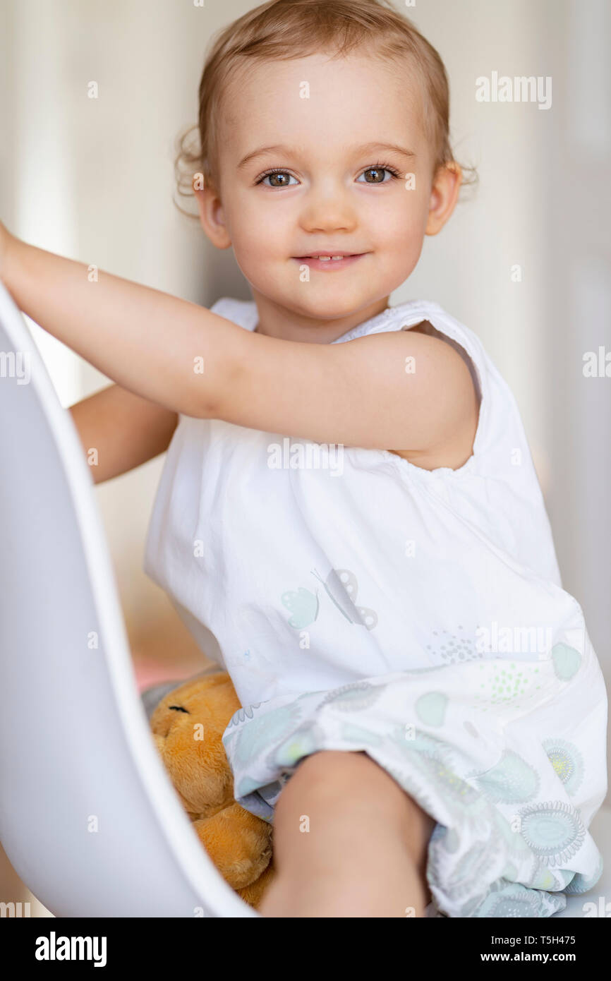Portrait of smiling toddler girl sitting on a chair Stock Photo - Alamy