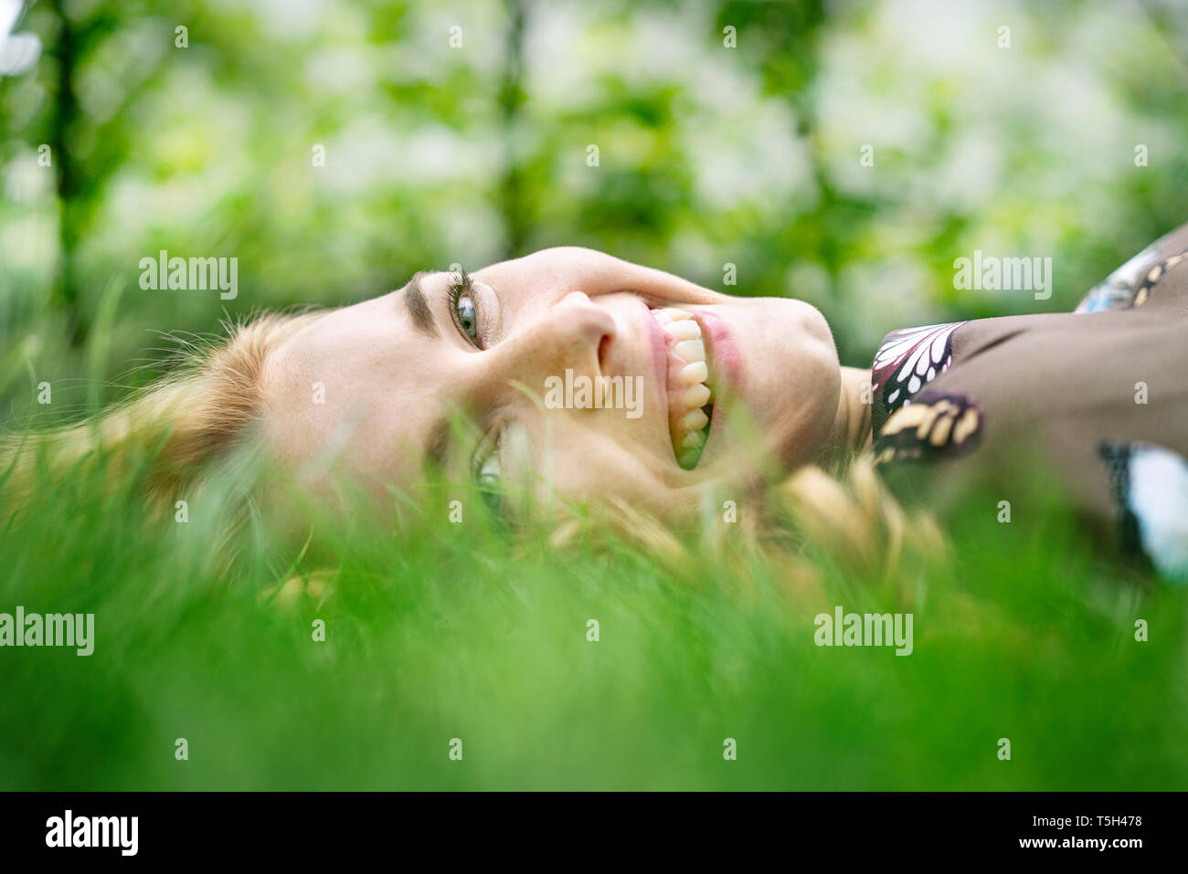 Cheerful young woman lying on grass, relaxing Stock Photo - Alamy
