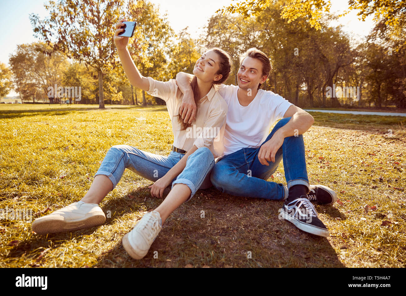 Young couple taking a selfie at a park Stock Photo - Alamy